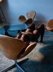 Black girl in stockings and heels sliding down a chair